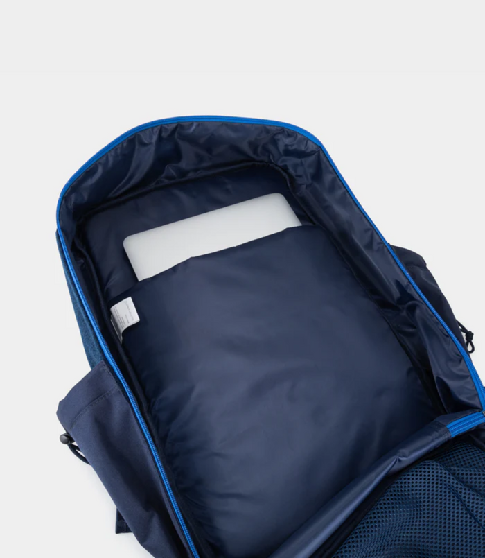 Interior upper section of the backpack with navy lining and a visible care label near the zipper.