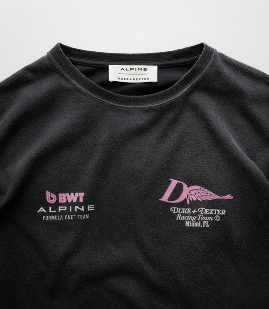 Close up of the white neck label reading ALPINE DUKE+DEXTER on a black Washed T-shirt