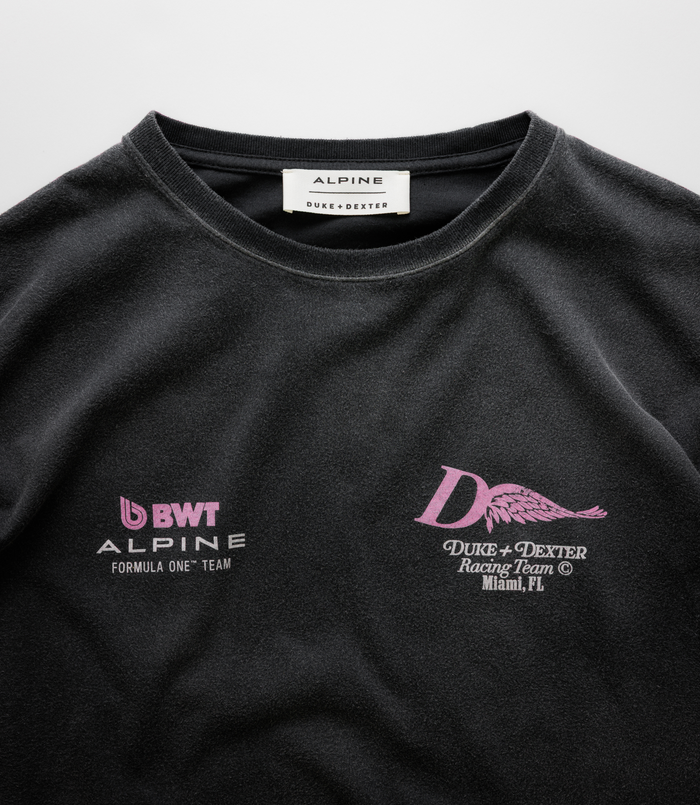 Close up of the white neck label reading ALPINE DUKE+DEXTER on a black Washed T-shirt