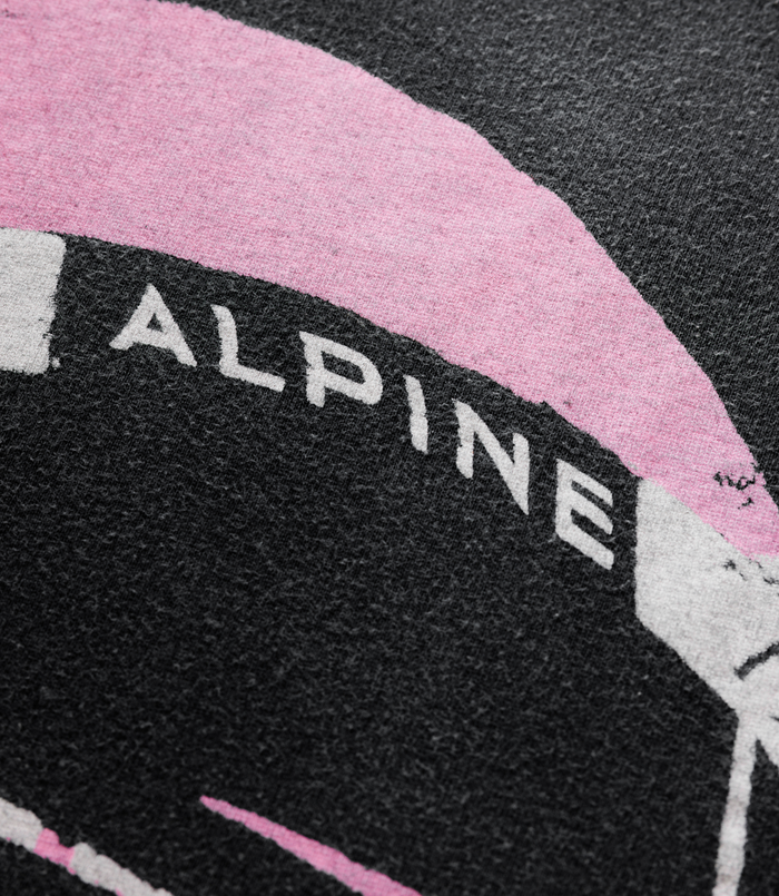 Detail of the pink wing graphic and white text from the Duke and Dexter BWT Alpine print on a black tee