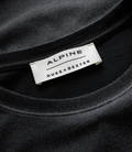 Close-up of white woven label on a black Duke and Dexter Helmet Washed Black T-shirt with Alpine branding.