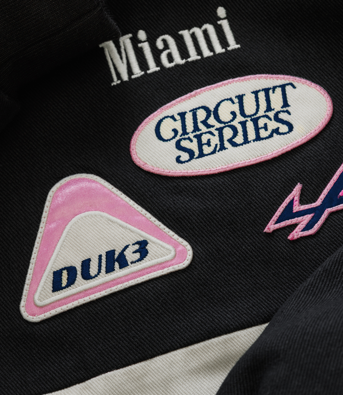 Mianni embroidery with a white oval patch featuring blue text and pink border on the jacket