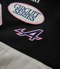 White oval patch with pink border and blue Circuit Series embroidery on black fabric