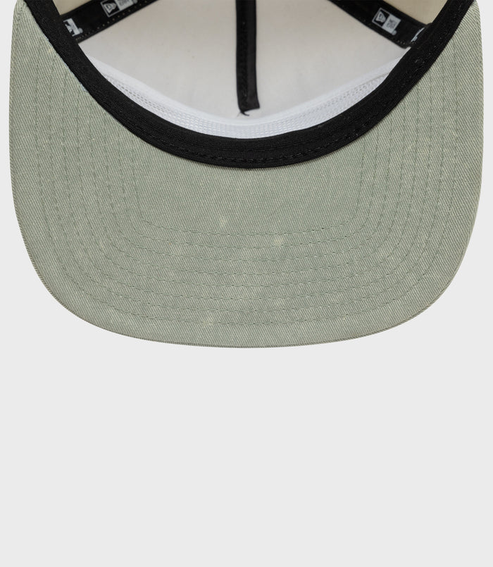 Close-up of olive green Alpine acid wash golfer cap front with black trim around the brim