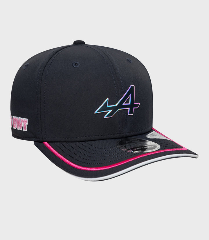 Angled shot of navy stretch snap cap showing iridescent logo on the front and pink brim edge