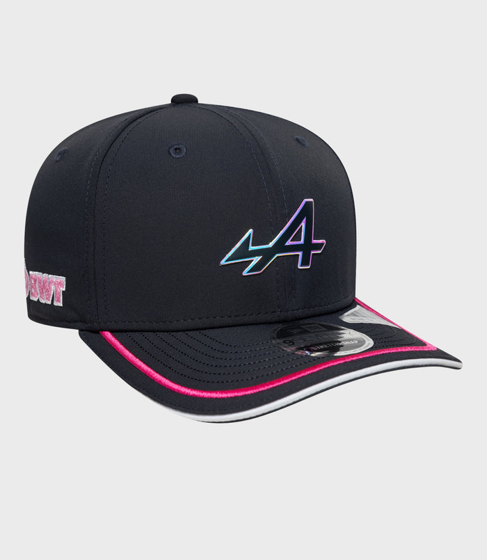 Angled shot of navy stretch snap cap showing iridescent logo on the front and pink brim edge
