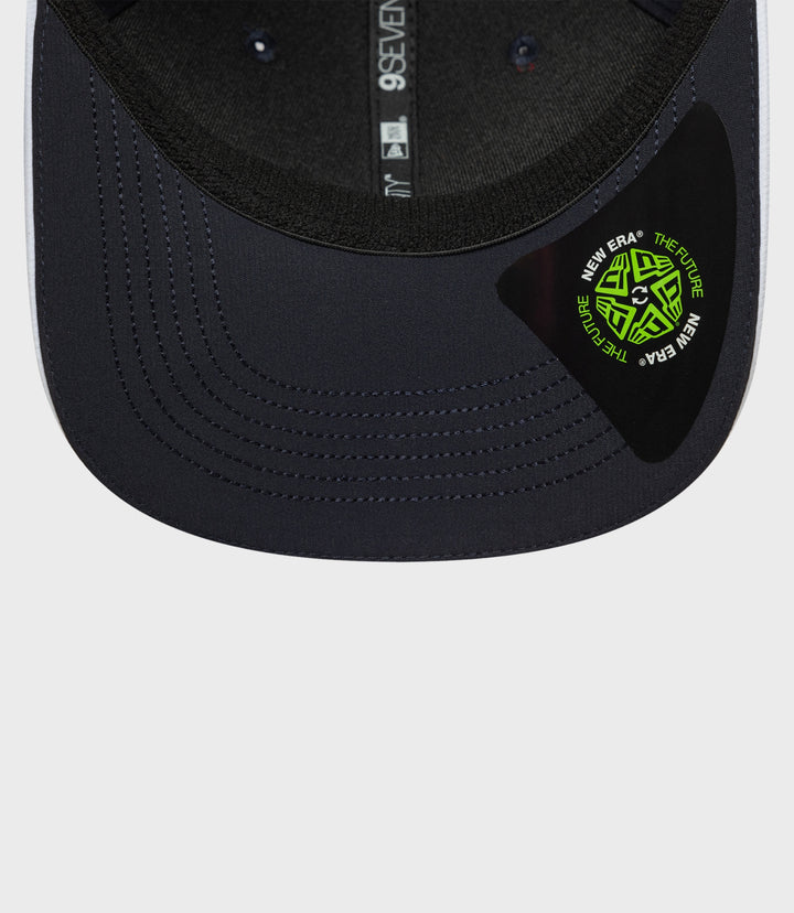 Navy cap brim close up showing neon green New Era sticker and rear strap
