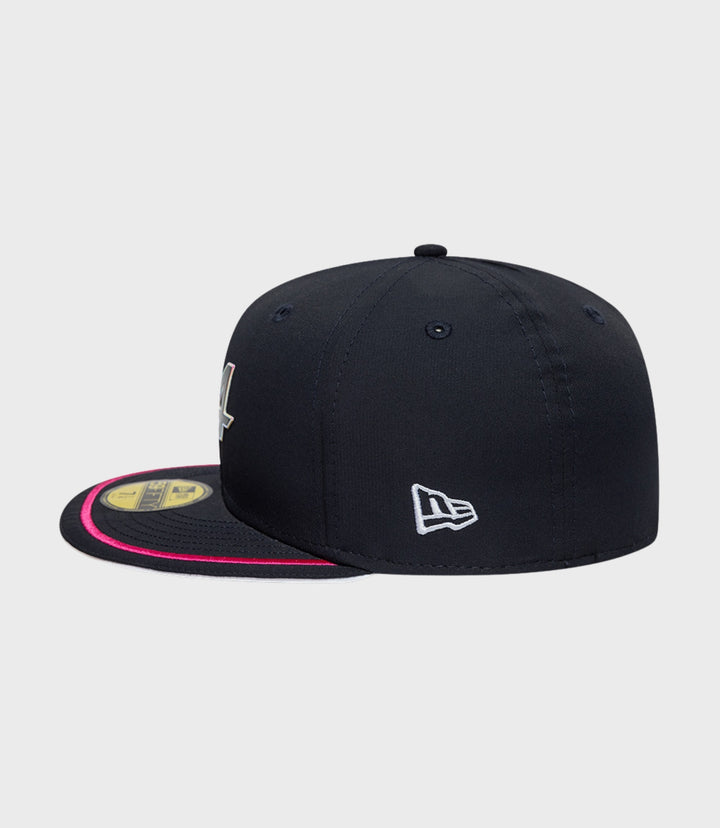 Side view of navy New Era Alpine 59Fifty cap with white logo on the side and pink brim trim