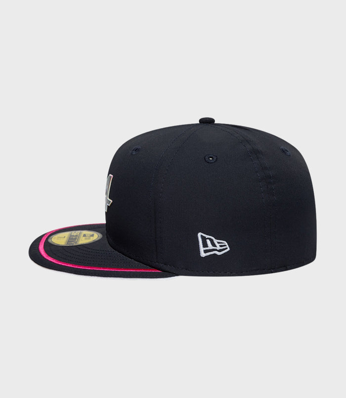 Side view of navy New Era Alpine 59Fifty cap with white logo on the side and pink brim trim