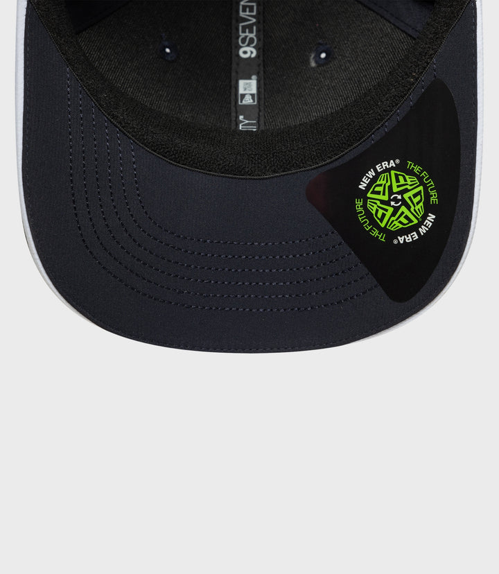 Interior view of navy 9Seventy cap showing vertical strap branding and a neon logo patch on the brim