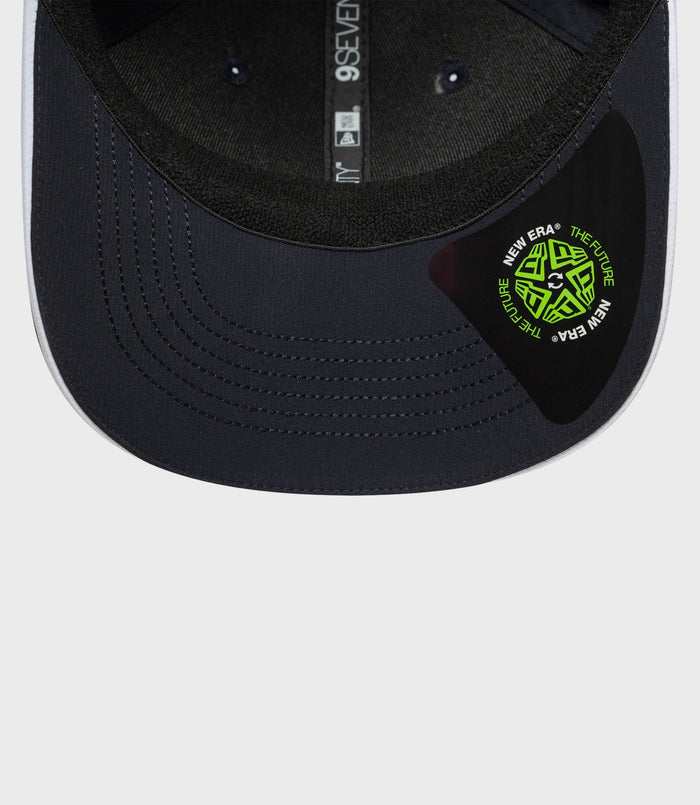 Interior view of navy 9Seventy cap showing vertical strap branding and a neon logo patch on the brim