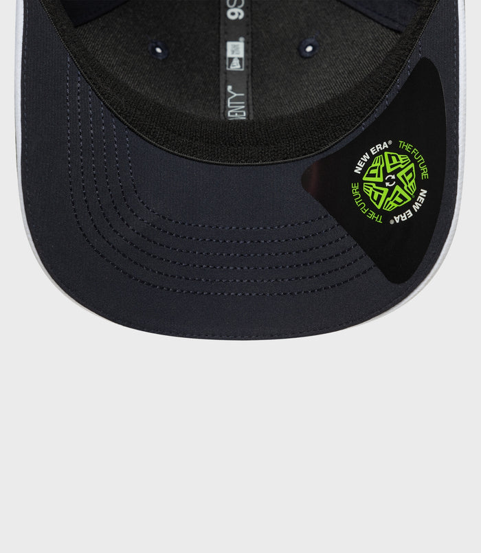 Close up of navy cap brim with pink edge and a green New Era circular patch sticker