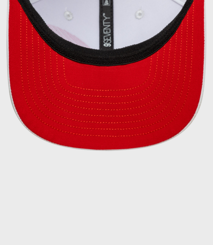 Close-up of the white cap brim with red stitching and a vertical 9Seventy label along the crown seam
