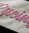 Pink embroidered patch with cursive lettering on light fabric of the jacket