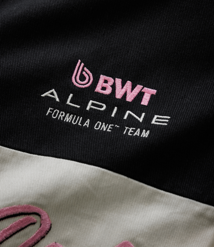 Close-up of black fabric with pink BWT embroidery and white Alpine lettering