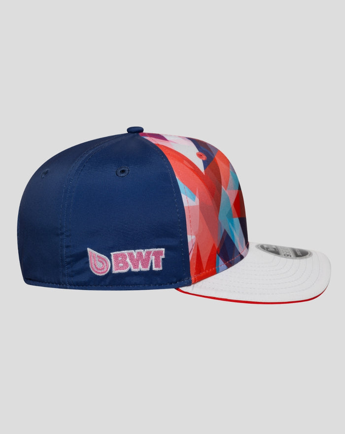 Back left angle showing the blue panel with pink BWT embroidery on the crown and the multicolor geometric pattern.