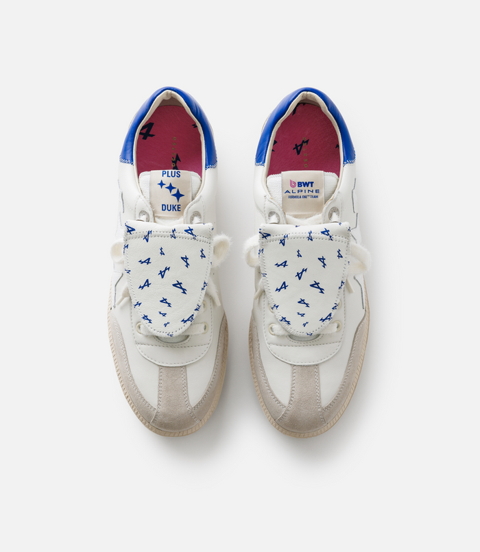 Top view of two white sneakers with blue interior lining and branded tongues showing Plus Duke and Alpine logos.