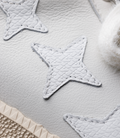 Close-up of light blue leather patch with quilted texture and white stitching on a white sneaker surface.