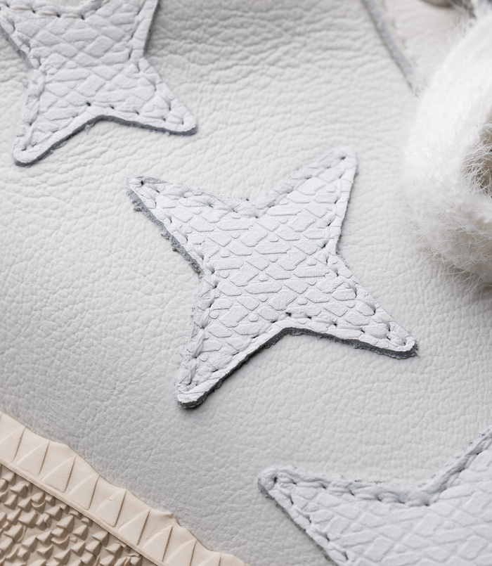 Close-up of light blue leather patch with quilted texture and white stitching on a white sneaker surface.