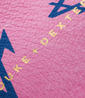 Pink textured leather surface with a blue graphic and gold foil lettering from the BWT Alpine collab