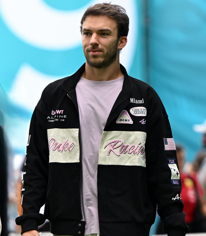 Male model wearing a Duke and Dexter racing jacket with pink Duke Racing script and various patches.