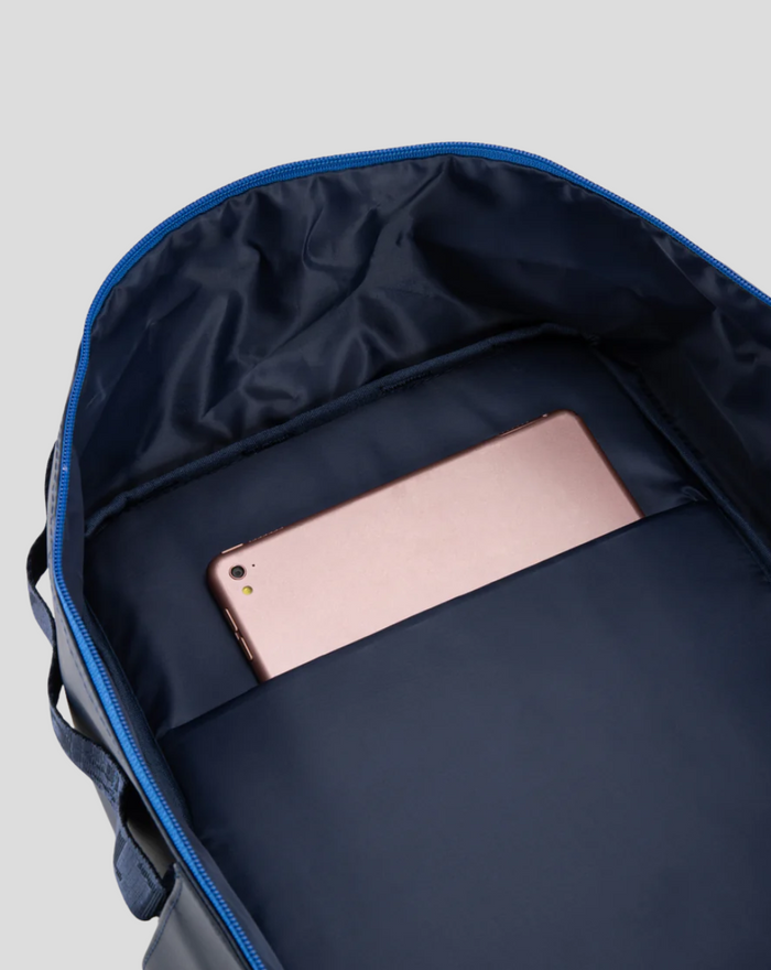 Inside the TYRO 20L backpack showing a navy lining and a rose gold smartphone tucked in the internal pocket