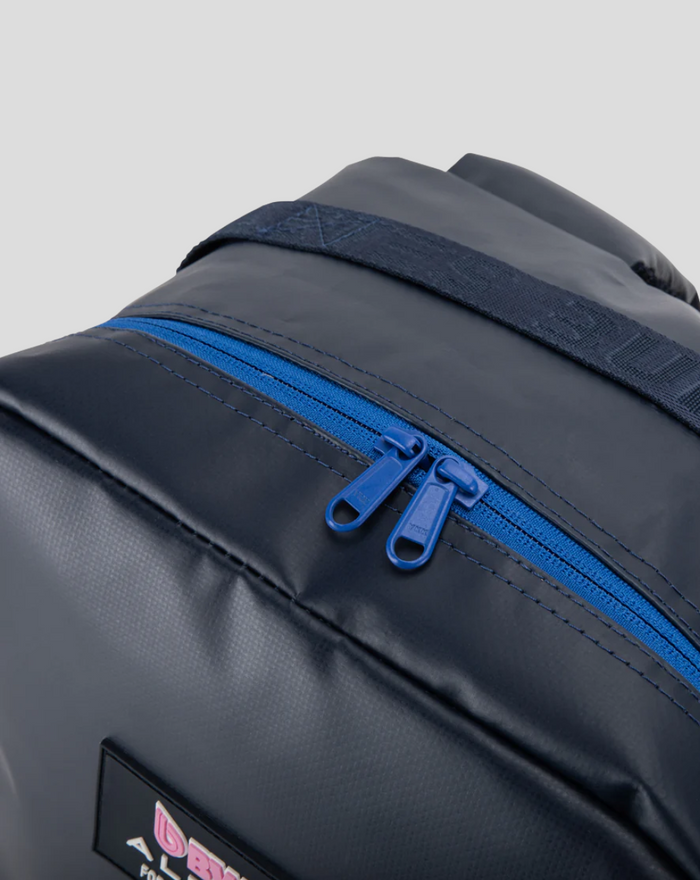 Close up of blue zipper on navy TYRO 20L backpack with strap detail.