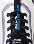 Close-up of a white Endstate sneaker showing black laces and a blue tongue tag with Alpine branding.