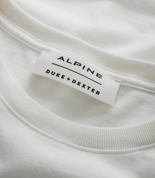 Close up of white T shirt showing a stitched Alpine label with Duke Dexter branding