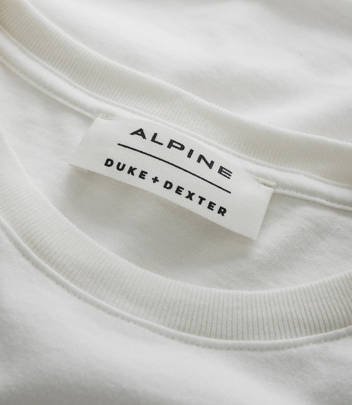 Close up of white T shirt showing a stitched Alpine label with Duke Dexter branding