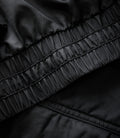 Close up of black fabric showing stitched elastic panel and quilting on the jacket.