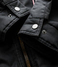 Close up of black trackside jacket fabric with metal snaps and visible zipper