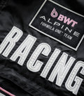 Close up of a black jacket showing the BWT Alpine patch with pink logo and Formula One Team embroidery.