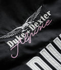 Close-up of white wing logo and pink script embroidery on black fabric jacket