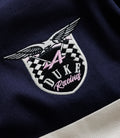 Close-up of embroidered badge on navy fabric with a winged crest, checkered pattern and pink Duke lettering.