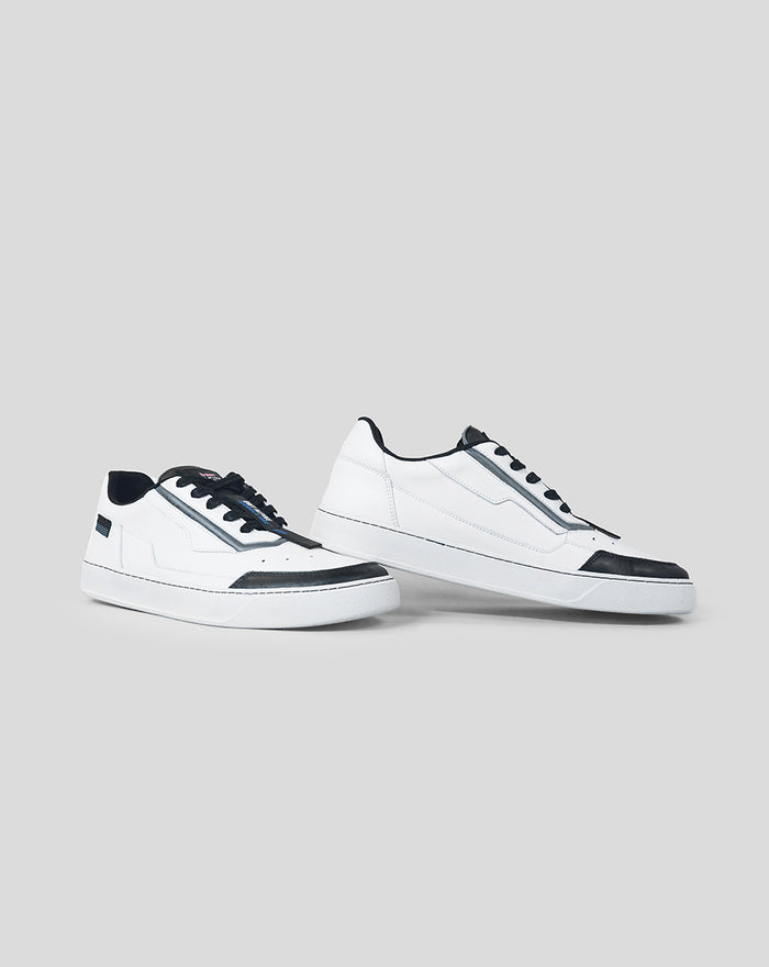 Side profile of white and black Endstate sneakers with black toe caps and blue detailing on gray background