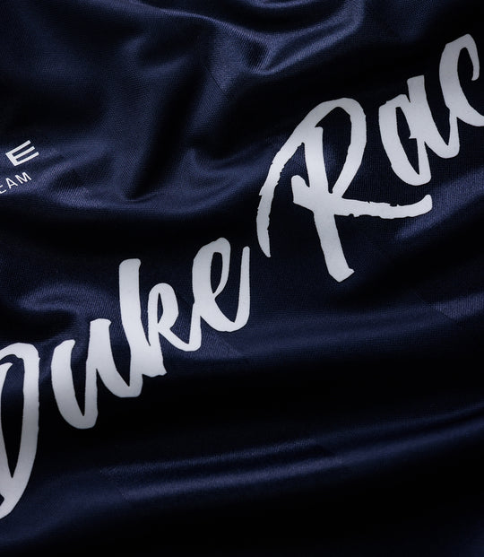 Close up of dark blue fabric with white Duke Racing script and team crest on a Duke & Dexter sports jersey