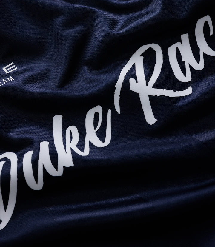 Close up of dark blue fabric with white Duke Racing script and team crest on a Duke & Dexter sports jersey