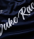 Close up of dark blue fabric with white Duke Racing script and team crest on a Duke & Dexter sports jersey