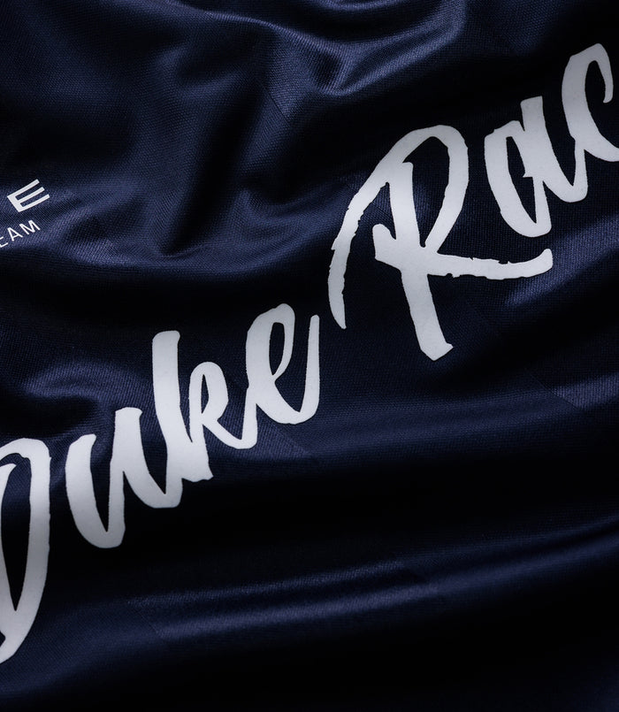Close up of dark blue fabric with white Duke Racing script and team crest on a Duke & Dexter sports jersey