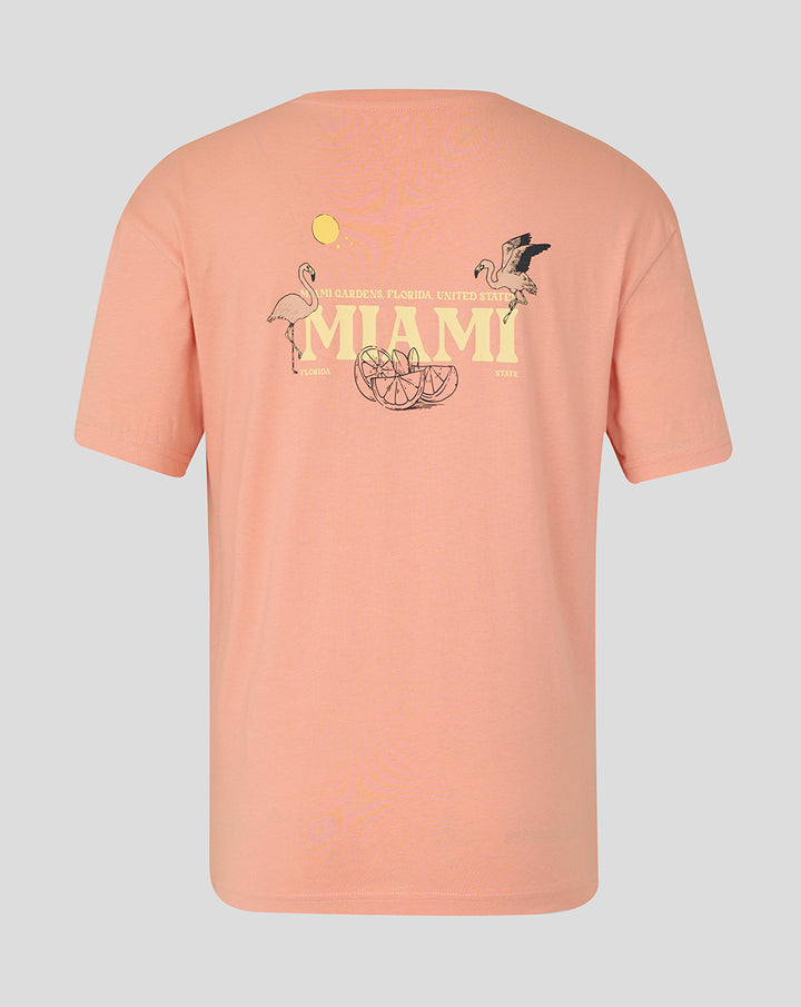 Back view of coral pink Miami graphic T-shirt with large MIAMI text and tropical flamingos and citrus slices.