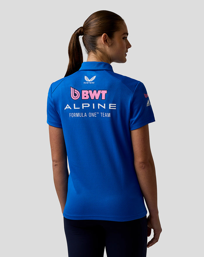 Rear three quarter view of a woman in a blue team polo showing sleeve logos and back branding