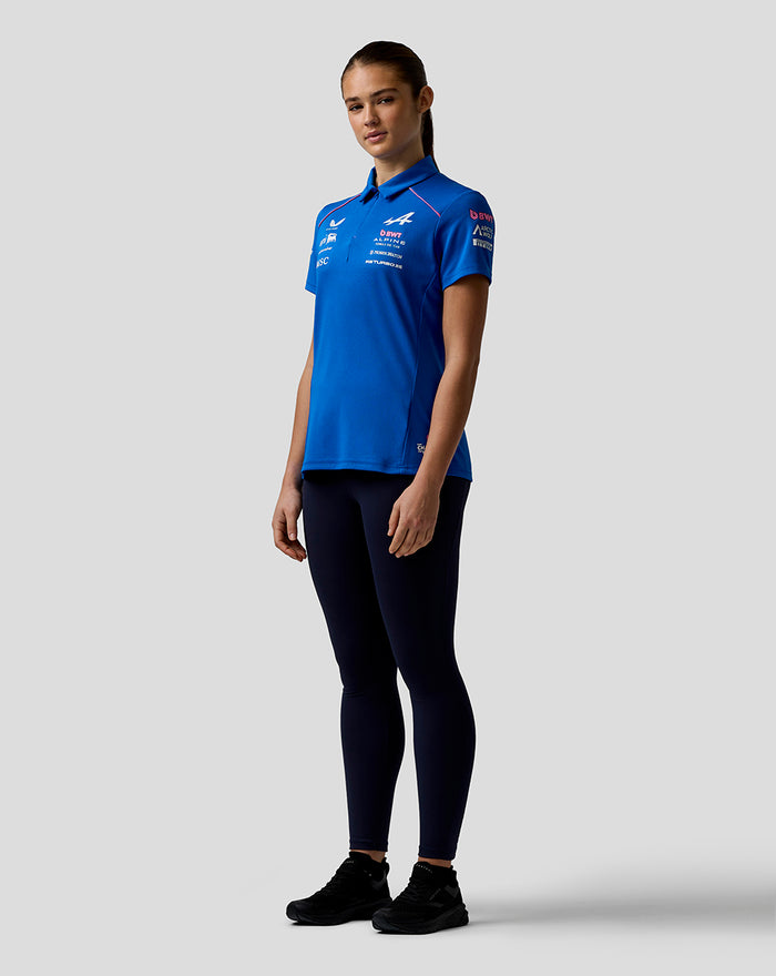 Model wearing blue Official Women’s BWT Alpine Formula One Team Polo Shirt with logos, paired with dark leggings and black sneakers