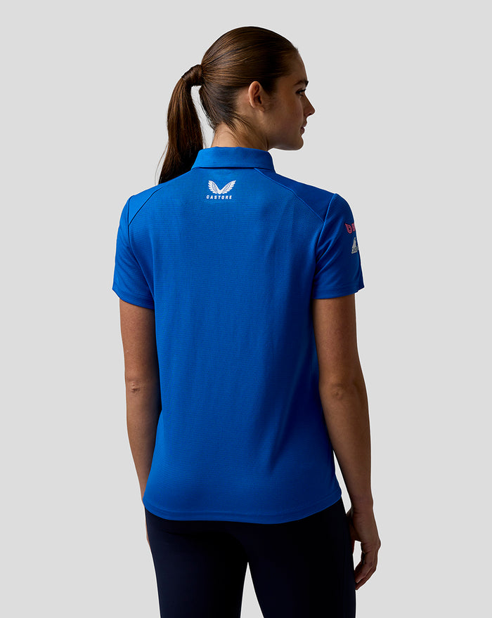 Back view of a woman wearing a blue BWT Alpine polo with a white Castore logo on the upper back.