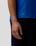 Close-up of blue AerTek polo fabric with texture and a small AERTEK label at the hem