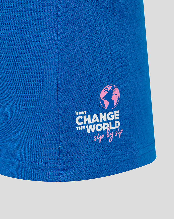 Blue polo shirt fabric close up with Change the World globe logo in white and pink on the hem