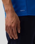 Close up of a blue Formula One Team Set Up T Shirt hem with AerTek logo and a resting hand.