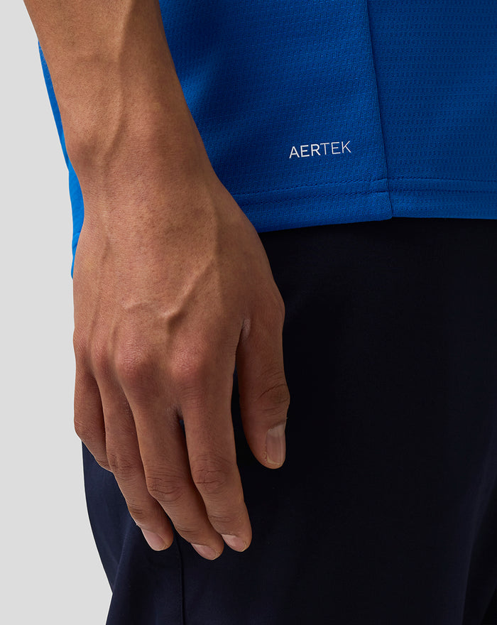 Close up of a blue Formula One Team Set Up T Shirt hem with AerTek logo and a resting hand.