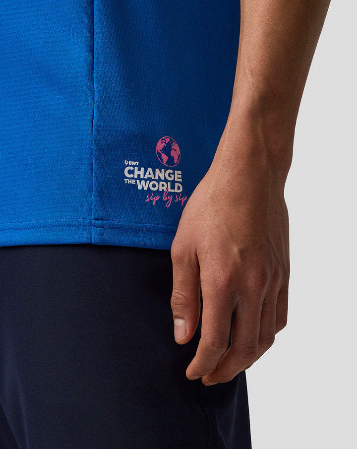 Close up of blue Formula One Team Set Up T Shirt with Change the World graphic on the hem and a resting hand.