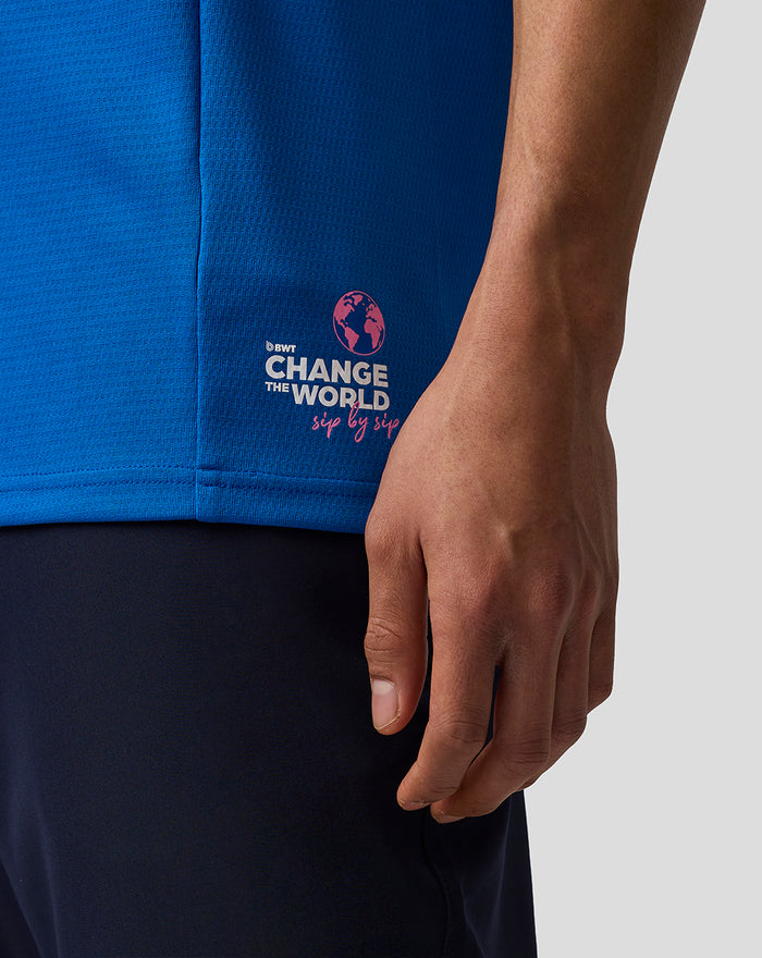 Close up of blue Formula One Team Set Up T Shirt with Change the World graphic on the hem and a resting hand.